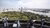 People on a rooftop deck using telescopes to view a river, bridge, and city skyline