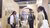 Four people chatting at a wood-paneled booth in a busy trade fair hall