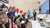 Audience seated indoors listening to presenter beside a large screen