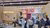 Visitors seated at wooden-panelled conference booth with purple arch and “50” banner