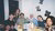 Six friends gathered around a dining table laden with food, smiling at the camera