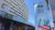 Modern curved concrete building next to colorful World Urban Forum banner under blue sky