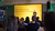 Presenter before yellow slide stating 'One in six people experience loneliness' to audience