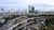 Curving elevated highways weaving through a cityscape with skyscrapers under cloudy sky