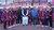 women athletes in tracksuits flanking male officials